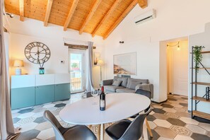 A modern interior with a round dining table, a sofa, a clock, and a kitchen area. - The Best View Apartment Torno (Torno)