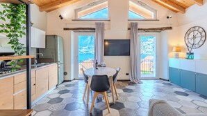Une cuisine moderne avec des meubles en bois, un coin repas doté d’une table ronde et de chaises, et une grande fenêtre donnant sur un paysage magnifique.
