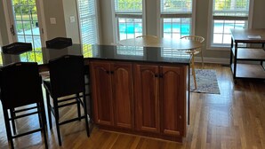 A spacious kitchen with a central island, pendant lighting, and a ceiling fan.