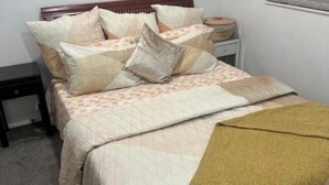 Una cama con edredón acolchado, almohadas y una manta.