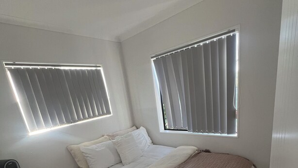 Un dormitorio con una cama, dos mesitas de noche, un calentador y dos ventanas con persianas.