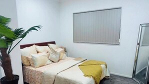 Un dormitorio con una cama, una planta en maceta, una ventana y un espejo.