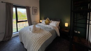 Ein Hotelzimmer mit einem großen Bett, einem Fenster mit Vorhängen, einer Wandleuchte und Blick nach draußen.