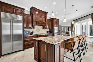 A spacious kitchen with dark wood cabinets, stainless steel appliances, and a granite countertop. - Sunshine Villa 6 bedrooms 6bathroom heated pool Clearwater (Clearwater)