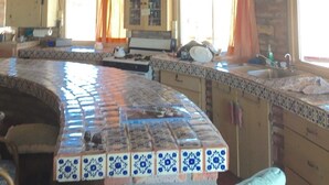 Una cocina rústica con salpicadero de azulejos, vigas de madera y pared de piedra.