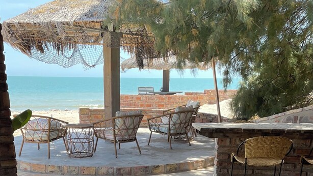 Un patio con mobiliario de mimbre, un muro de ladrillo y vista al mar.