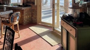 Een rustieke keuken met stenen muren, een houten plafond en een schuifdeur van glas naar een terras.
