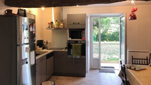 A compact kitchen with a refrigerator, microwave, and oven. A sliding glass door leads to a patio. - Grand Mas, 32 hectares, nature and reunion (Mirepoix)