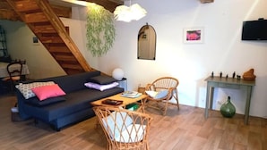 A cozy living room with a sofa, two wicker chairs, a small table, a TV, and a staircase. - Grand Mas, 32 hectares, nature and reunion (Mirepoix)