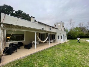 A house with a patio, outdoor furniture, and a person walking in the yard.