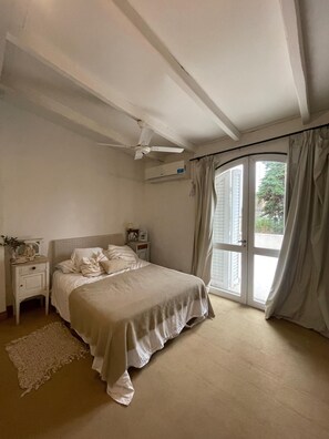 A bedroom with a bed, a nightstand, a ceiling fan, and a window with curtains.
