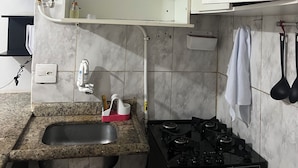 Een keuken met witte kasten, een granieten aanrecht, een gasfornuis en een spoelbak.