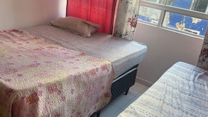 Een slaapkamer met twee bedden, een raam met uitzicht en een gordijn.