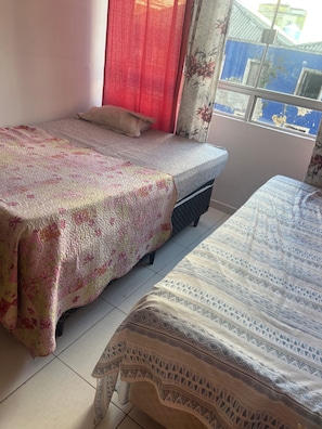 Ein Schlafzimmer mit zwei Betten, einem Fenster mit Blick und einem Vorhang.