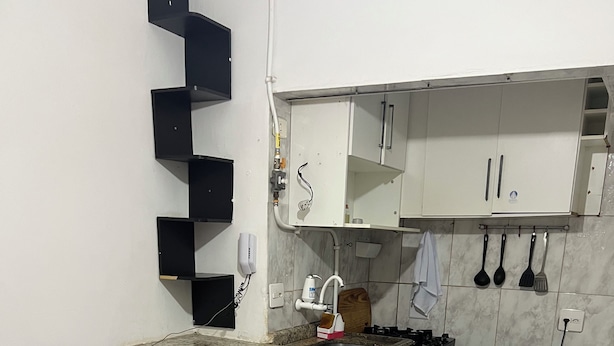 Een compacte keuken met een rode bank, een ingebouwd aanrecht en witte kasten.