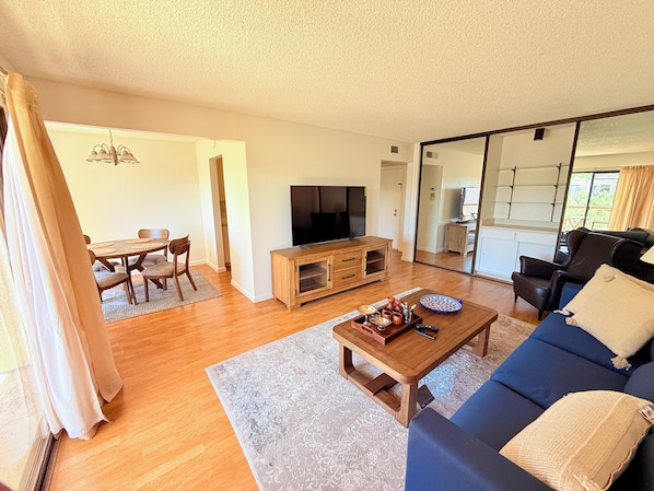 A living room with a sofa, coffee table, TV, and dining area.