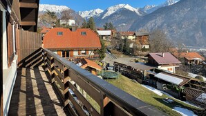 A wooden balcony overlooking a village with snow-capped mountains in the background. - Superb apartment in a country house (Passy)