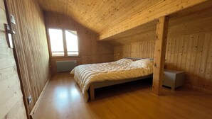 A bedroom with a wooden ceiling, a bed, a nightstand, and a window. - Superb apartment in a country house (Passy)