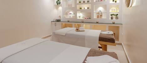 A spa room with two beds, a reception desk, and shelves with products.