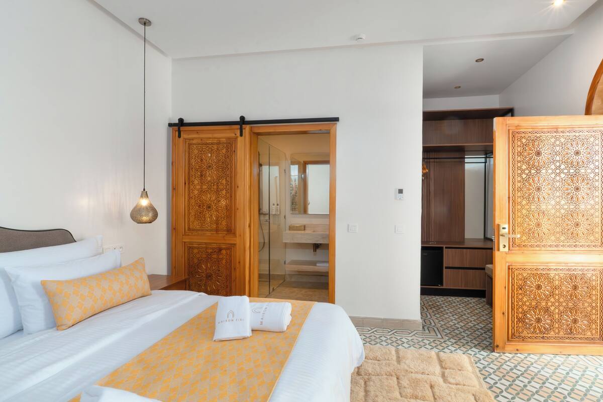 A hotel room with a bed, a wardrobe, a bathroom, and a kitchenette.