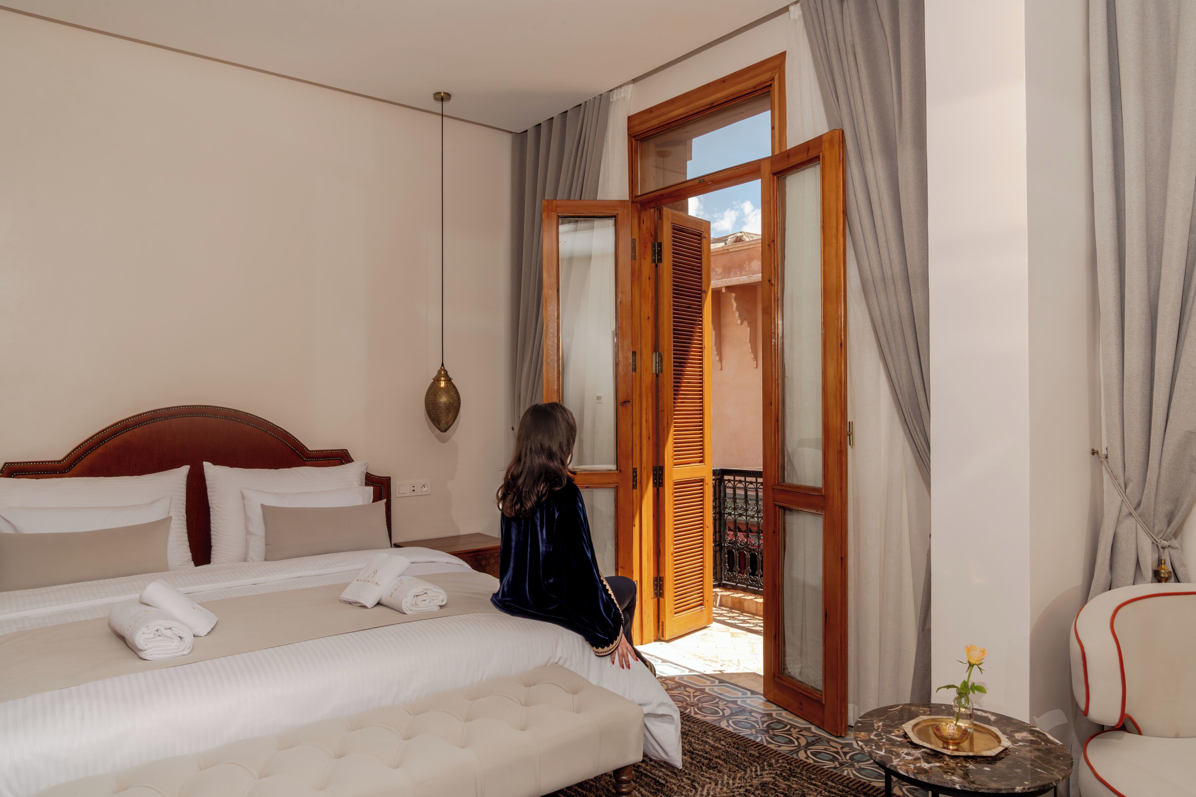 Una habitación de hotel con cama, una silla, una mesita y un balcón.