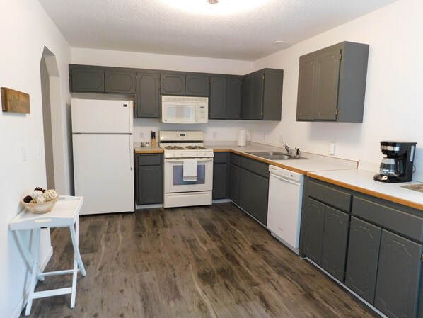 A compact kitchen with a refrigerator, stove, microwave, sink, and dishwasher.