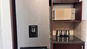 A kitchen with a stainless steel refrigerator, a microwave, and a water dispenser. - Stylish 1-bed in Bryanston (Johannesburg)