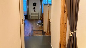 Ein Flur mit Holztürrahmen, weißer Wand und einem Fenster mit Vorhängen.