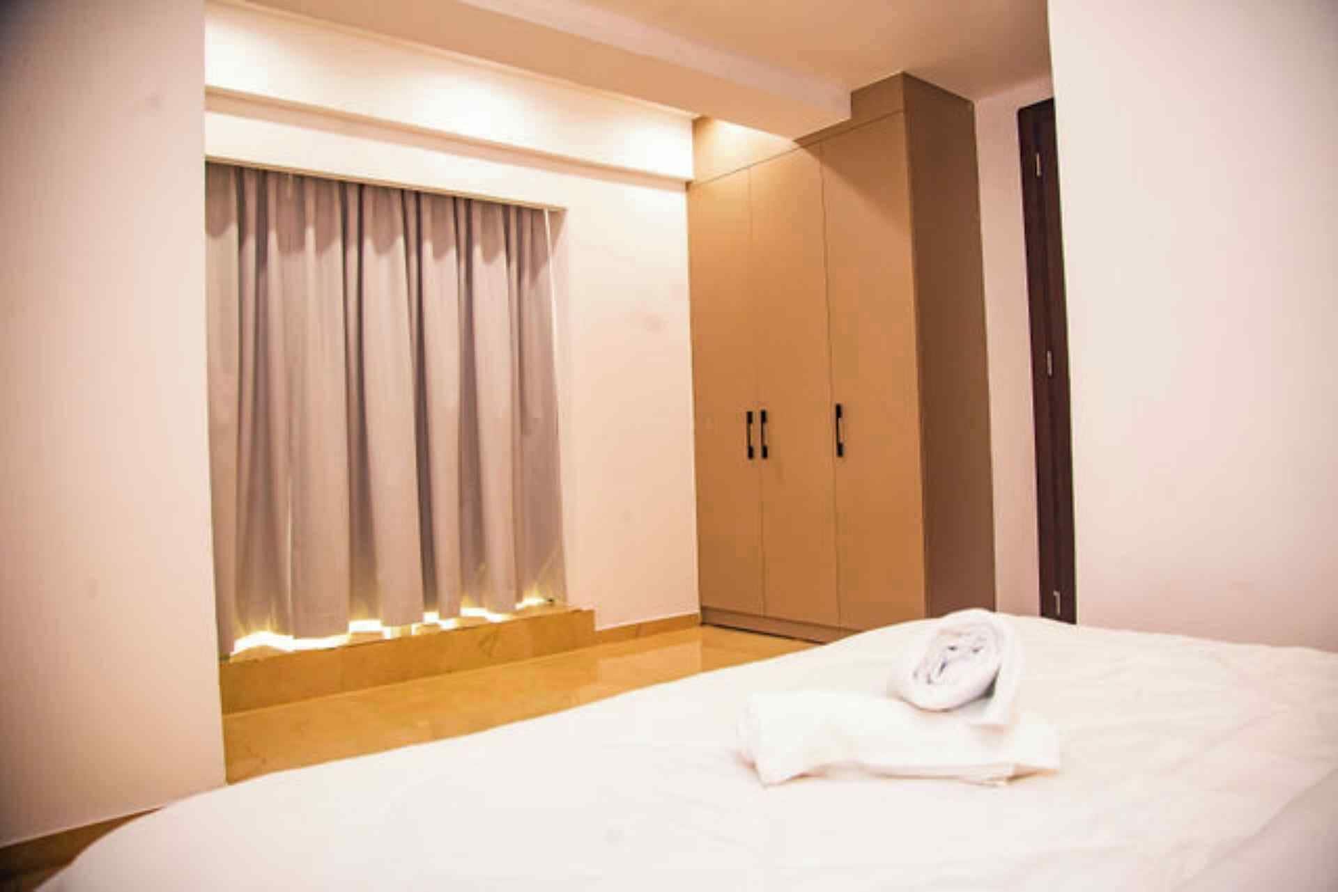 A hotel room with a bed, a wardrobe, and a window with curtains.