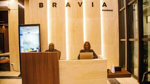 Vastaanottotiski, jossa on puuviimeistely ja suuri näyttö. Tiskin yläpuolella näkyy sana ”BRAVIA”, ja oikealla puolella on teksti ”Residency”.