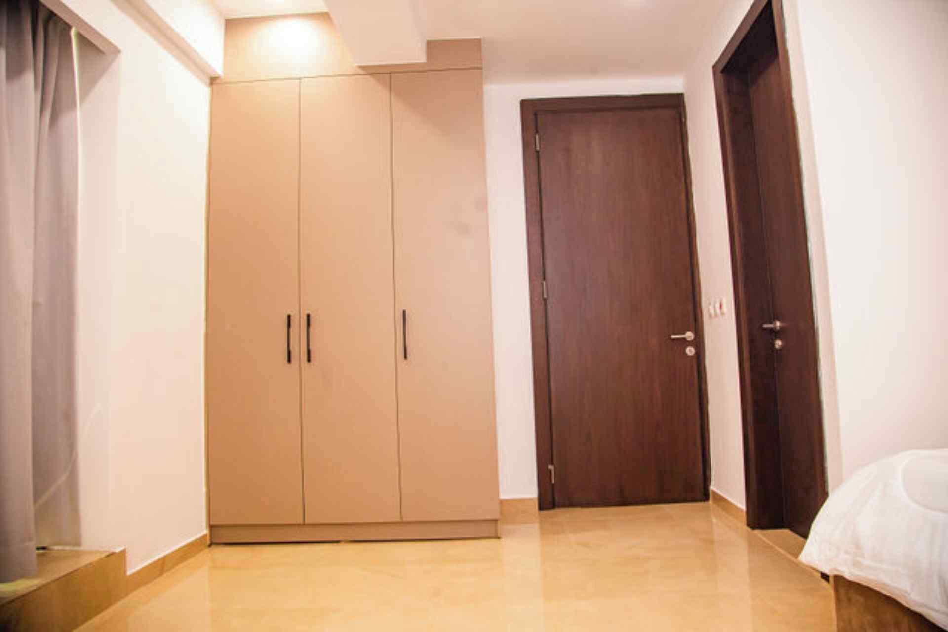 A room with a wardrobe, a door, and a bed.