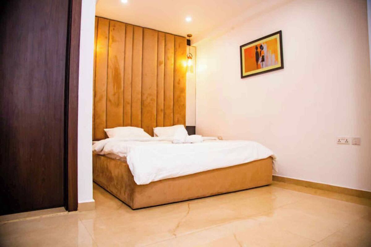 A bedroom with a wooden headboard, a bed with white bedding, and a framed picture on the wall.