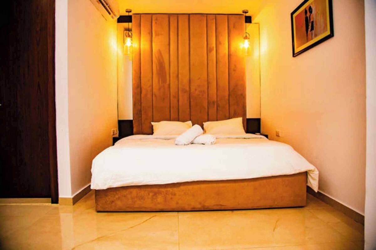 A hotel room with a wooden headboard, a large bed, and two wall-mounted light fixtures.