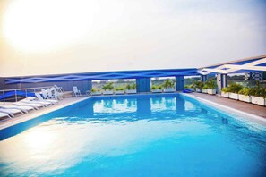 Ein Pool auf dem Dach mit Liegestühlen und Topfpflanzen.