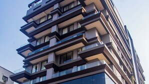 Monikerroksinen rakennus, jossa on parvekkeita, suuret ikkunat ja moderni arkkitehtoninen ilme.