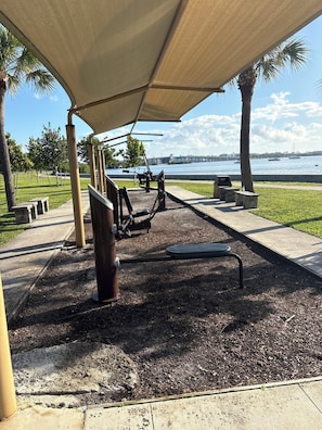 An outdoor exercise area with a view of a body of water and a bridge in the distance.