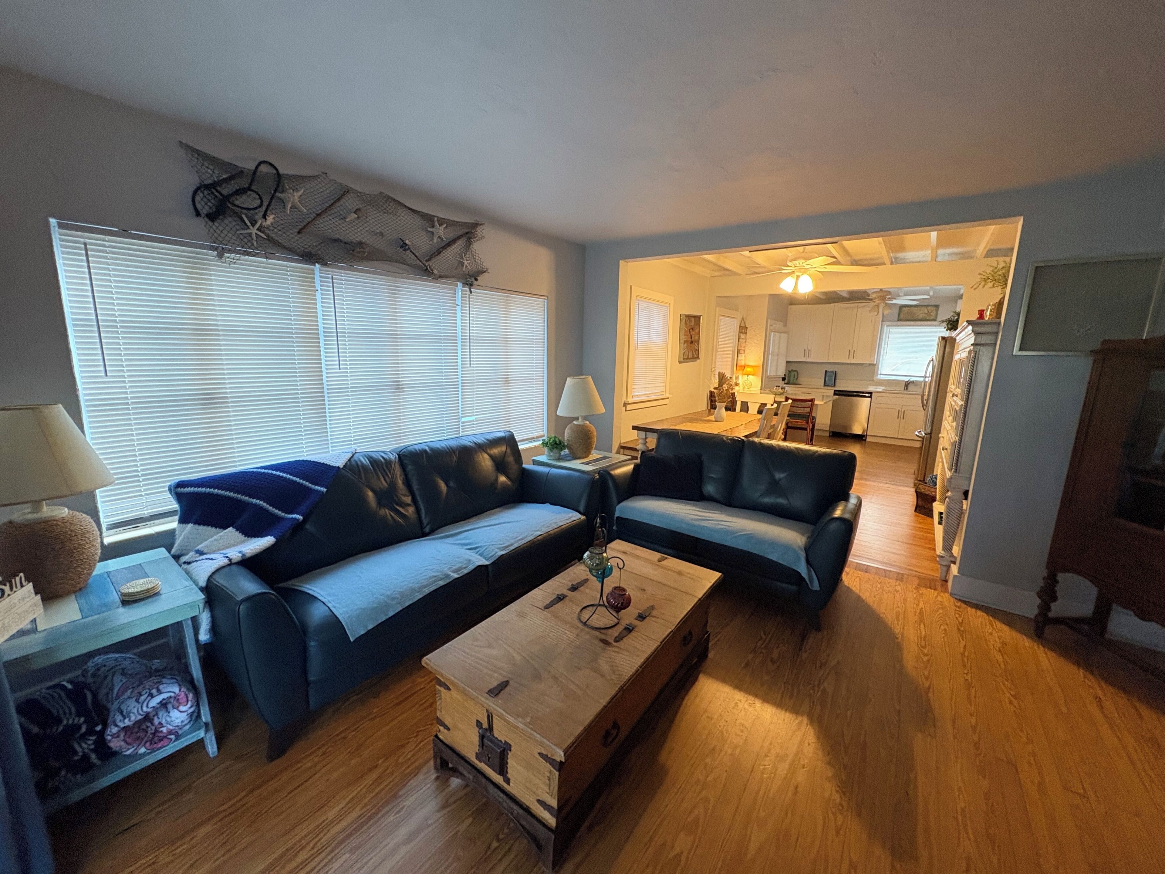 Ein Wohnzimmer mit einer Couch, einem Holztisch, einer Lampe und einem Fenster mit Jalousien.