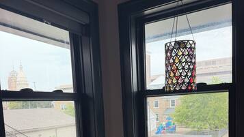 A room with two windows, a decorative hanging light, and a small plant on a dresser.