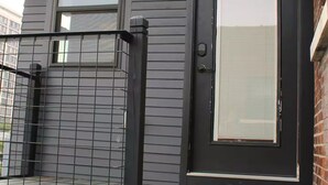 A house with a dark gray exterior, a black front door with a glass panel, and a small porch area. - Urban Garden Loft - Historic Charm & Bold Design (Lansing)