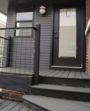 A house with a dark gray exterior, a black front door with a glass panel, and a small porch area.