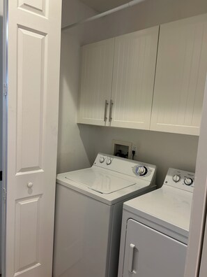 A laundry room with two washing machines, a dryer, and white cabinets. - Sandestin, 1 BR/2 Bath, Sleeps 4, Golf Cart Available! (Miramar Beach)