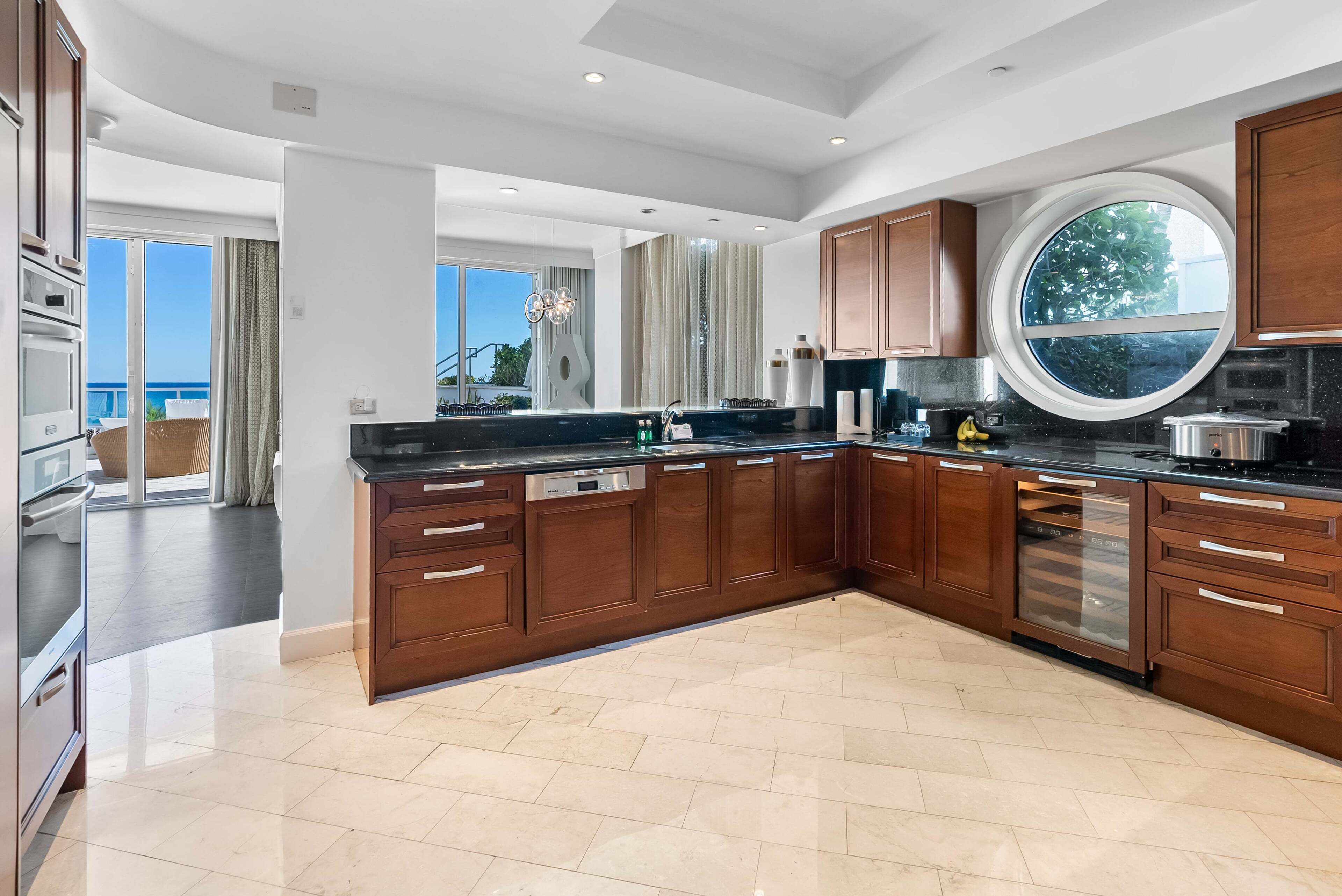 A modern kitchen with wooden cabinets, a large island, and a view of the outdoors.