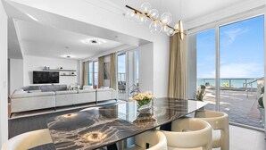 A modern living room with a large glass table, white sofas, and a TV. - Sorrento 512 (Miami Beach)
