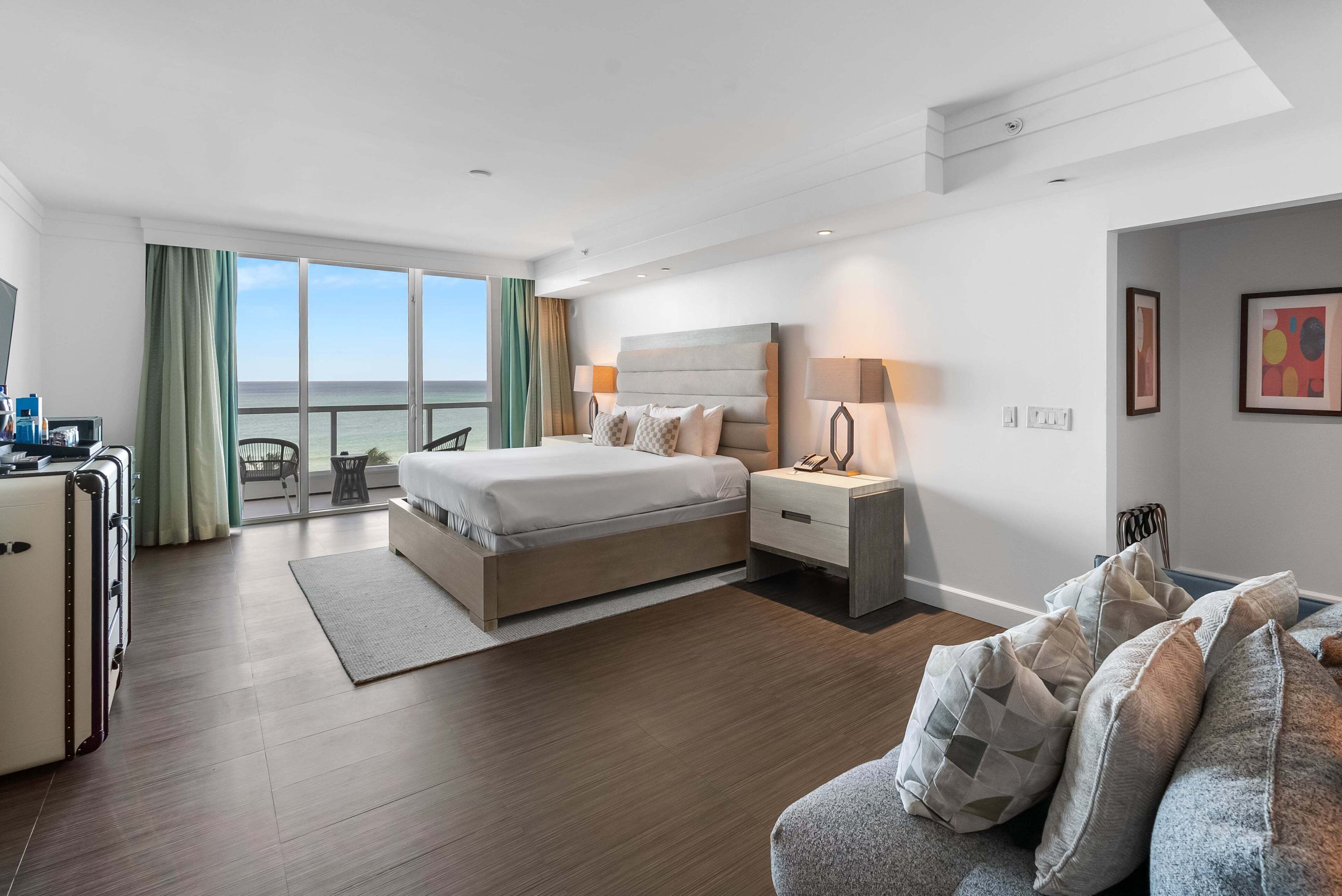 Ein modernes Hotelzimmer mit Bett, Nachttischen, einem Schreibtisch und Meerblick.
