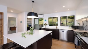 A modern kitchen with a central island, built-in appliances, and large windows offering a view of the outdoors.