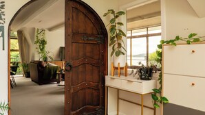 A room with a large wooden door, a white desk with drawers, a mirror, and a view of a balcony.