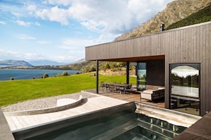 Une maison moderne avec une piscine, un espace salon extérieur et une vue sur la mer.