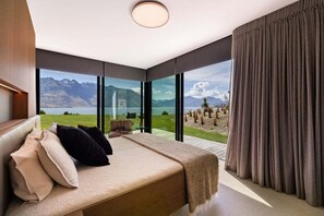 Une chambre avec un grand lit, donnant sur un lac, et avec des montagnes en arrière-plan.