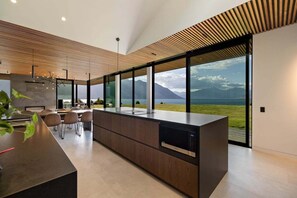 Une cuisine moderne dotée d’un grand îlot central, d’un coin repas et de grandes fenêtres offrant une vue sur les montagnes.