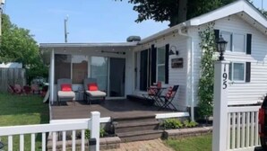 A mobile home with a deck, outdoor seating, and a mailbox.